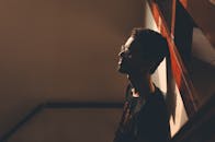 从上方看，一个戴眼镜、留着胡子的年轻男子靠在家里的墙上