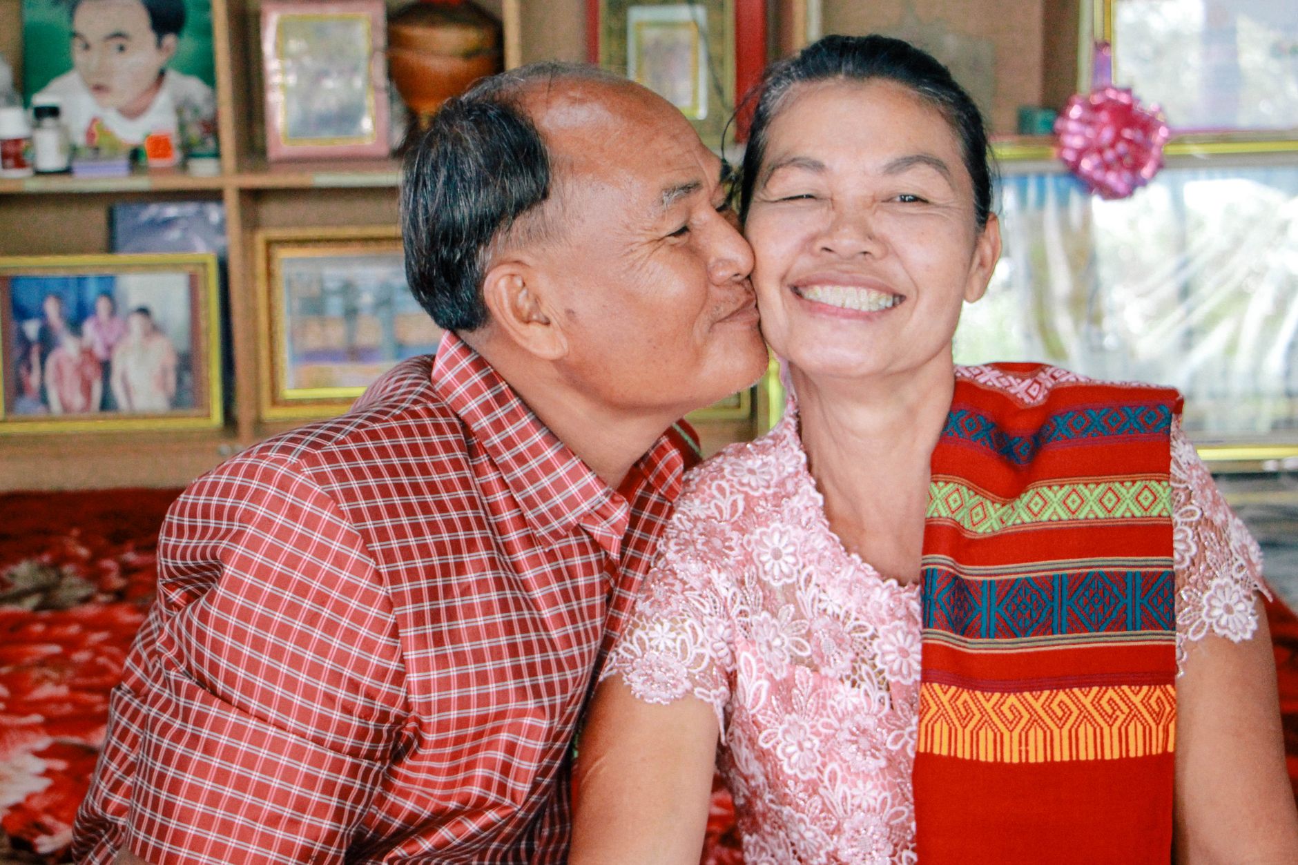 Smiling elderly couple embracing affectionately indoors, showcasing love and togetherness.