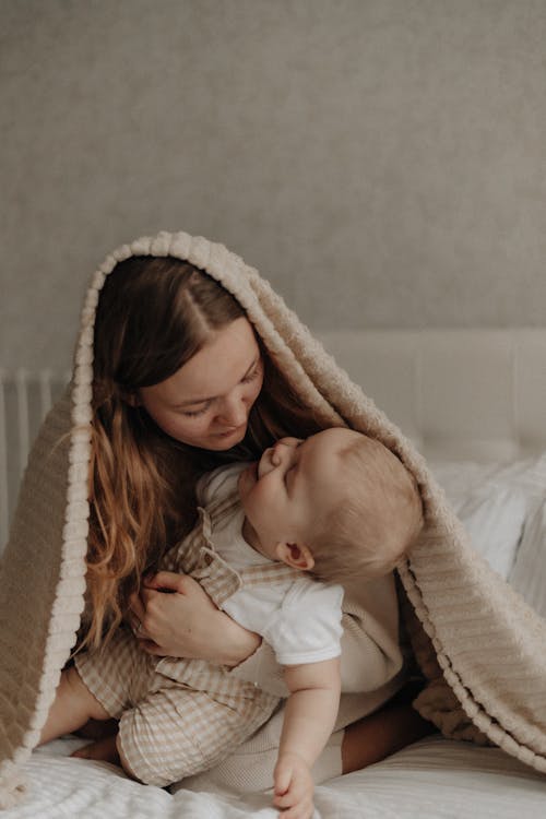 A woman and a baby are wrapped in blankets