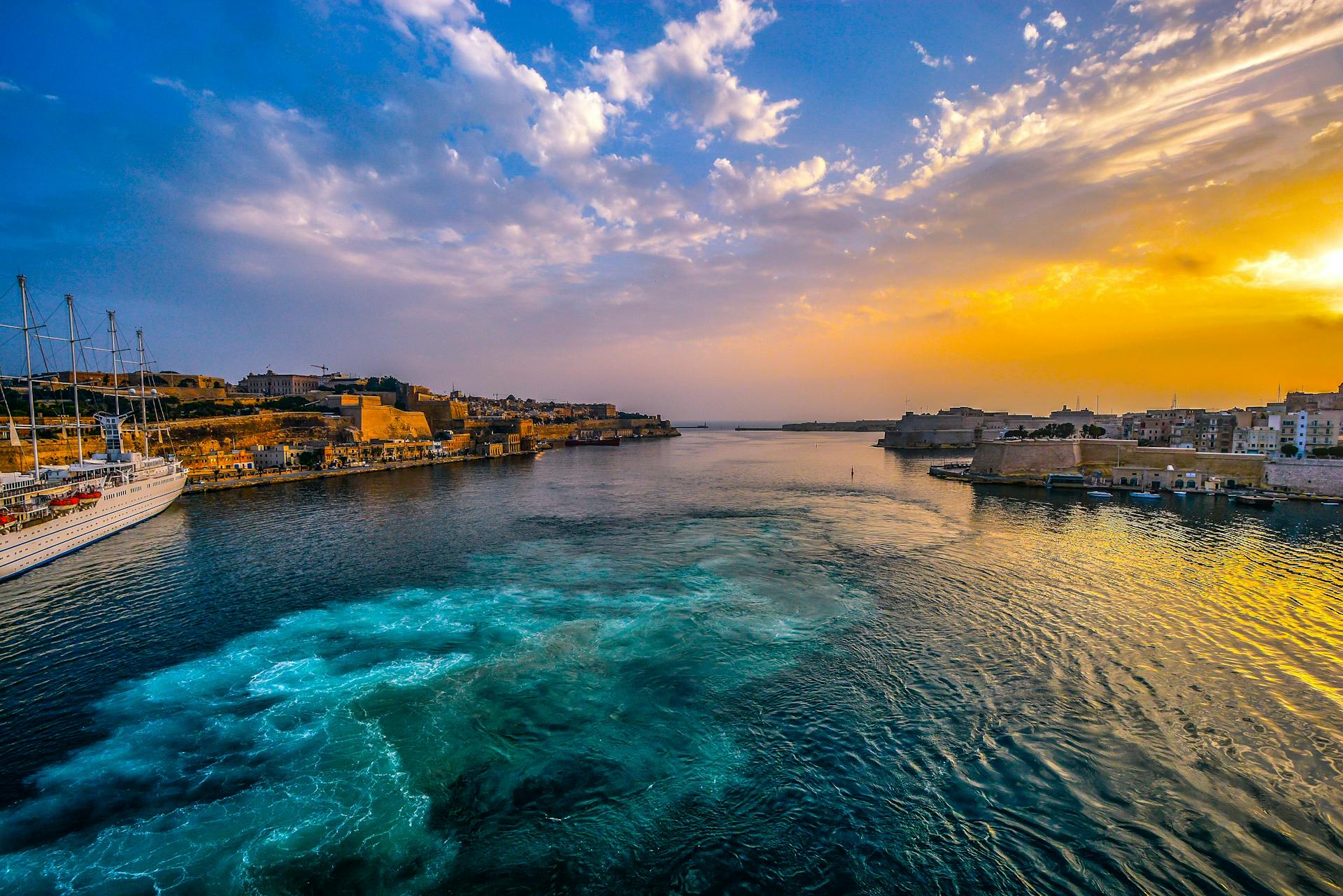 Vibrant Mediterranean seascape with stunning sunset over the sea and coastal landmarks.
