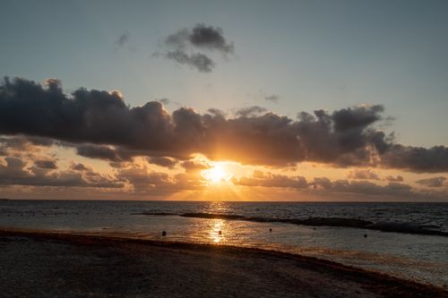 Free Serene sunset with clouds over Playa del Carmen's sandy beach in Mexico. Stock Photo