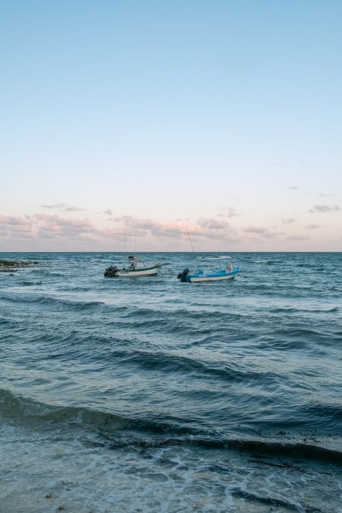 Free Capture of small boats on gentle waves at Playa del Carmen during sunset. Stock Photo