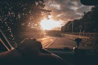 在风景优美的道路上，于日落时分驾驶，享受宁静，仰望充满活力的天空