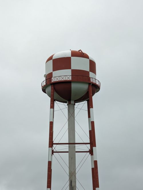 Free Vertical shot of a red and white checkered water tower against a cloudy sky in Canada. Stock Photo