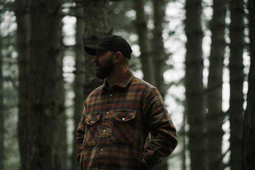 Free A man in a plaid shirt stands in the woods Stock Photo