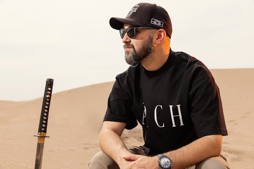 Free A man in a baseball cap sitting in the desert Stock Photo