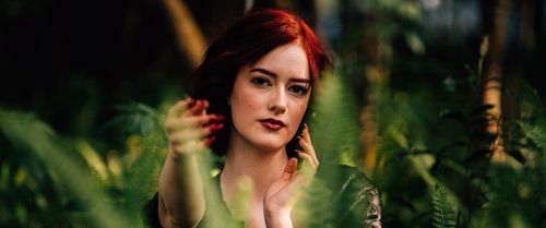 Free Striking portrait of a woman amidst lush fern foliage, bathed in natural light. Stock Photo