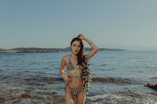A woman in a leopard print bikini standing on the beach