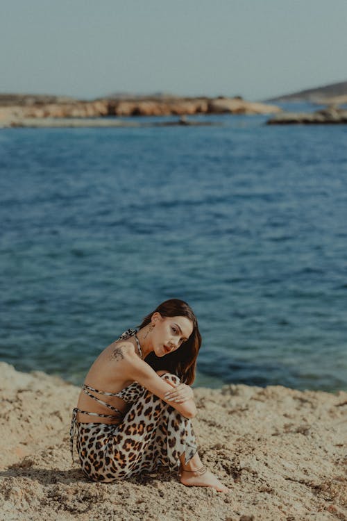 A woman in leopard print pants sitting on the beach