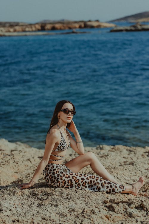 A woman in leopard print pants sitting on the rocks