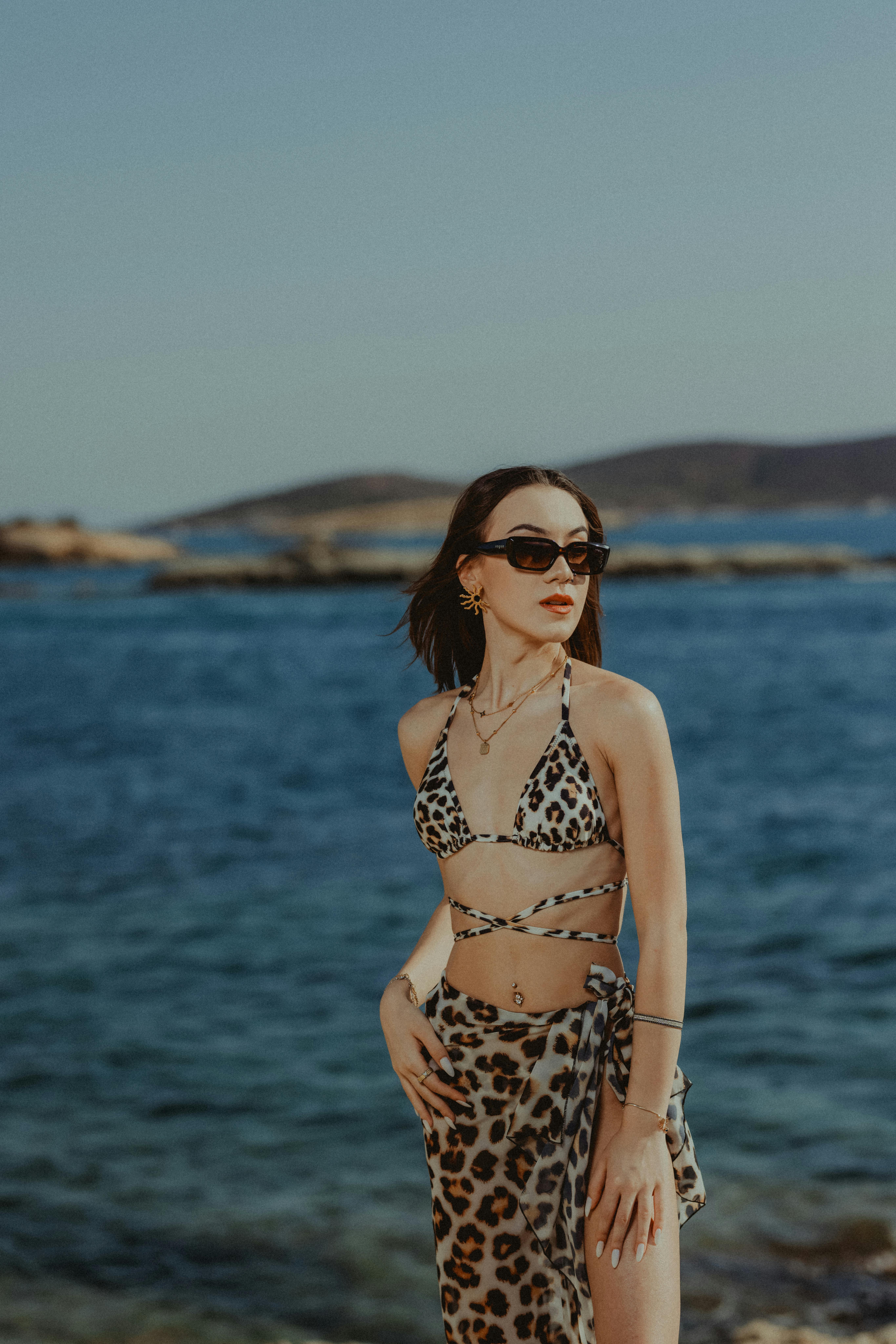 Woman in leopard bikini and sunglasses posing at the beach on a summer day.