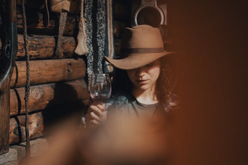 A woman in a hat is holding a glass of wine