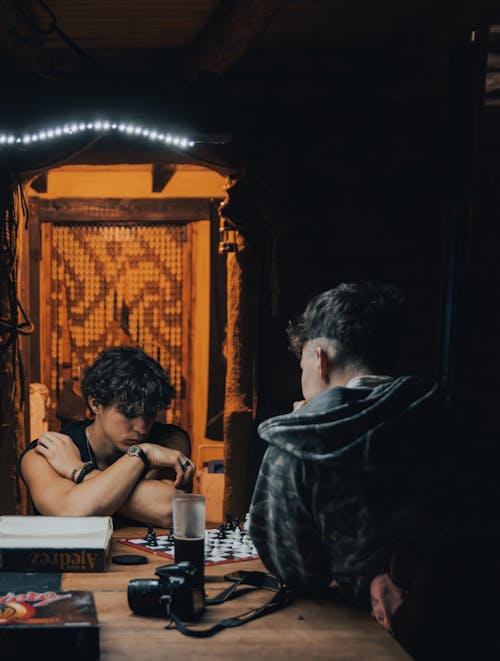 Two people sitting at a table playing chess