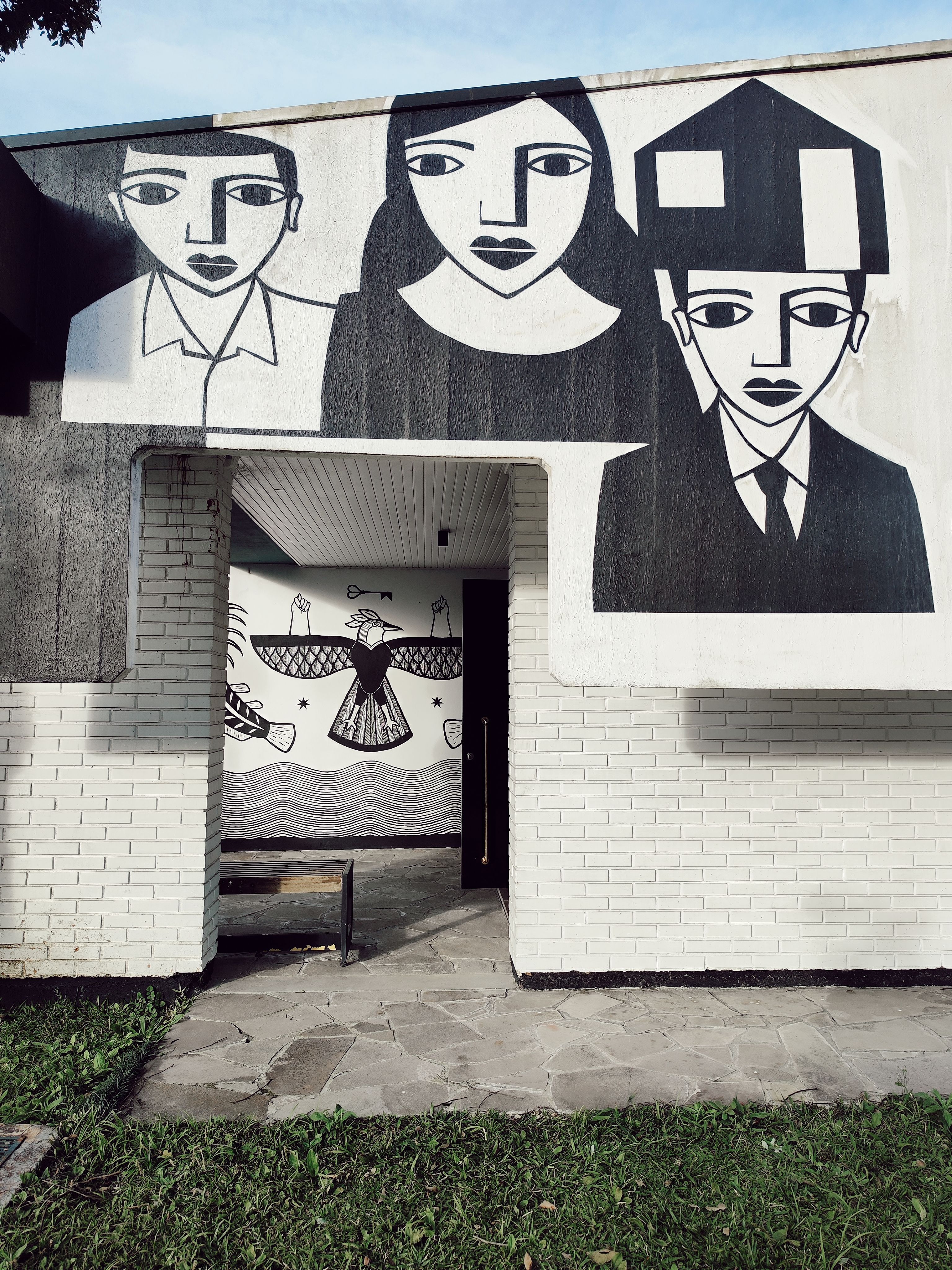 Striking black and white mural on a modern building facade in an urban park.