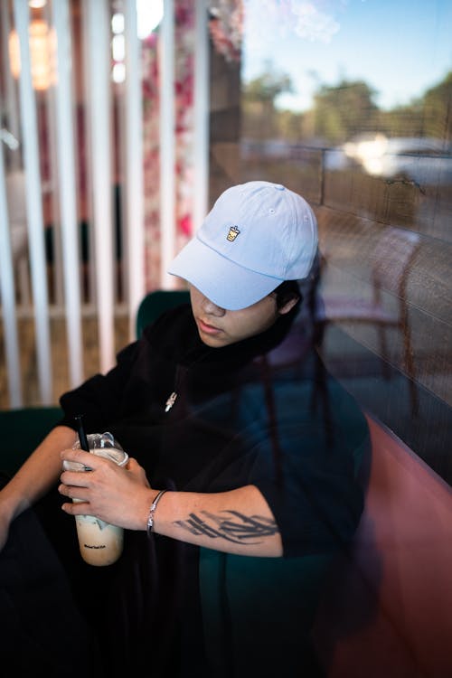 A man with tattoos sitting in a chair with a cup of coffee