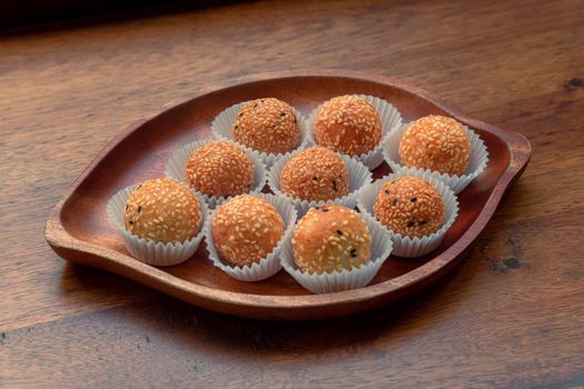 Close-up of Vietnamese sesame balls on a wooden tray, showcasing their golden texture.