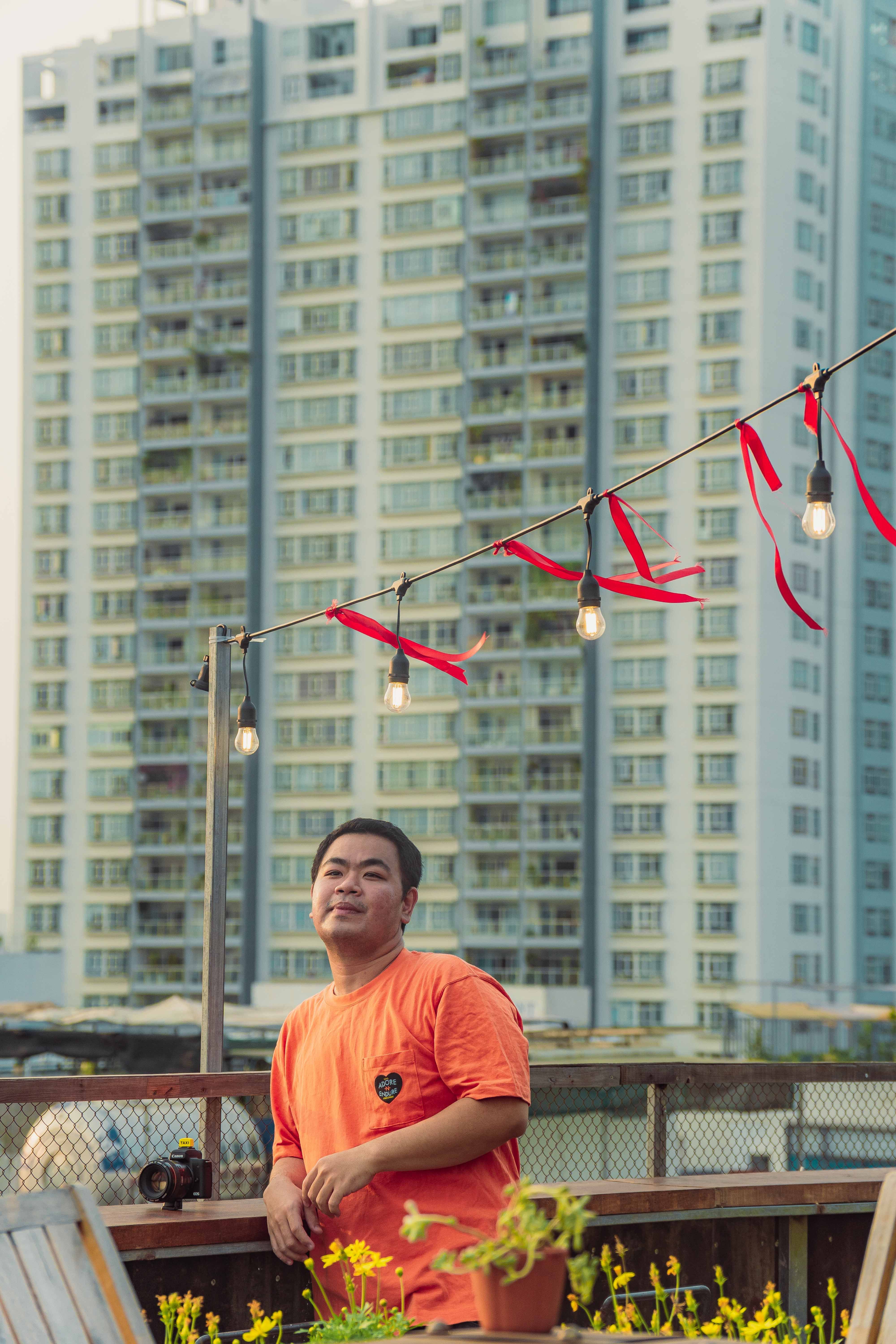 Asian man poses on a rooftop with cityscape background in Ho Chi Minh City, Vietnam.