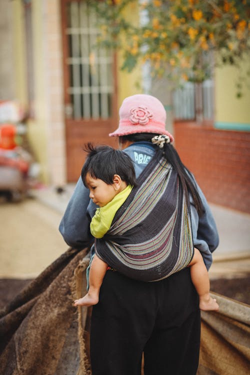 A woman carrying a child in a sling