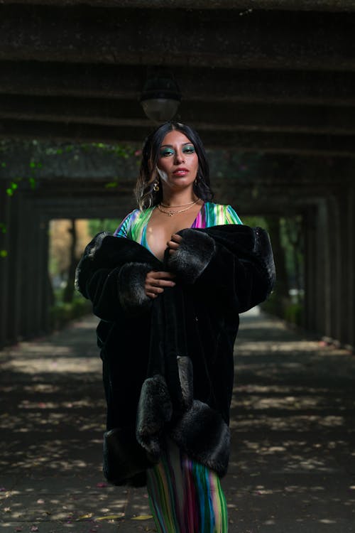 A woman in a colorful striped dress and fur coat