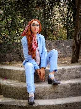Fashion-forward woman with red hair in a blue suit sitting on stone steps outdoors in Mexico City.