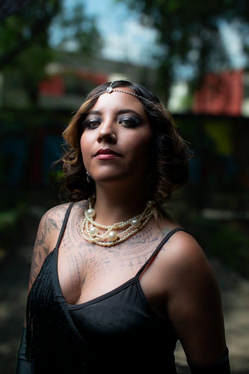 A woman with tattoos and jewelry poses for a photo