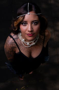 Fashion portrait of a woman in a black dress and jewelry, showcasing tattoos.