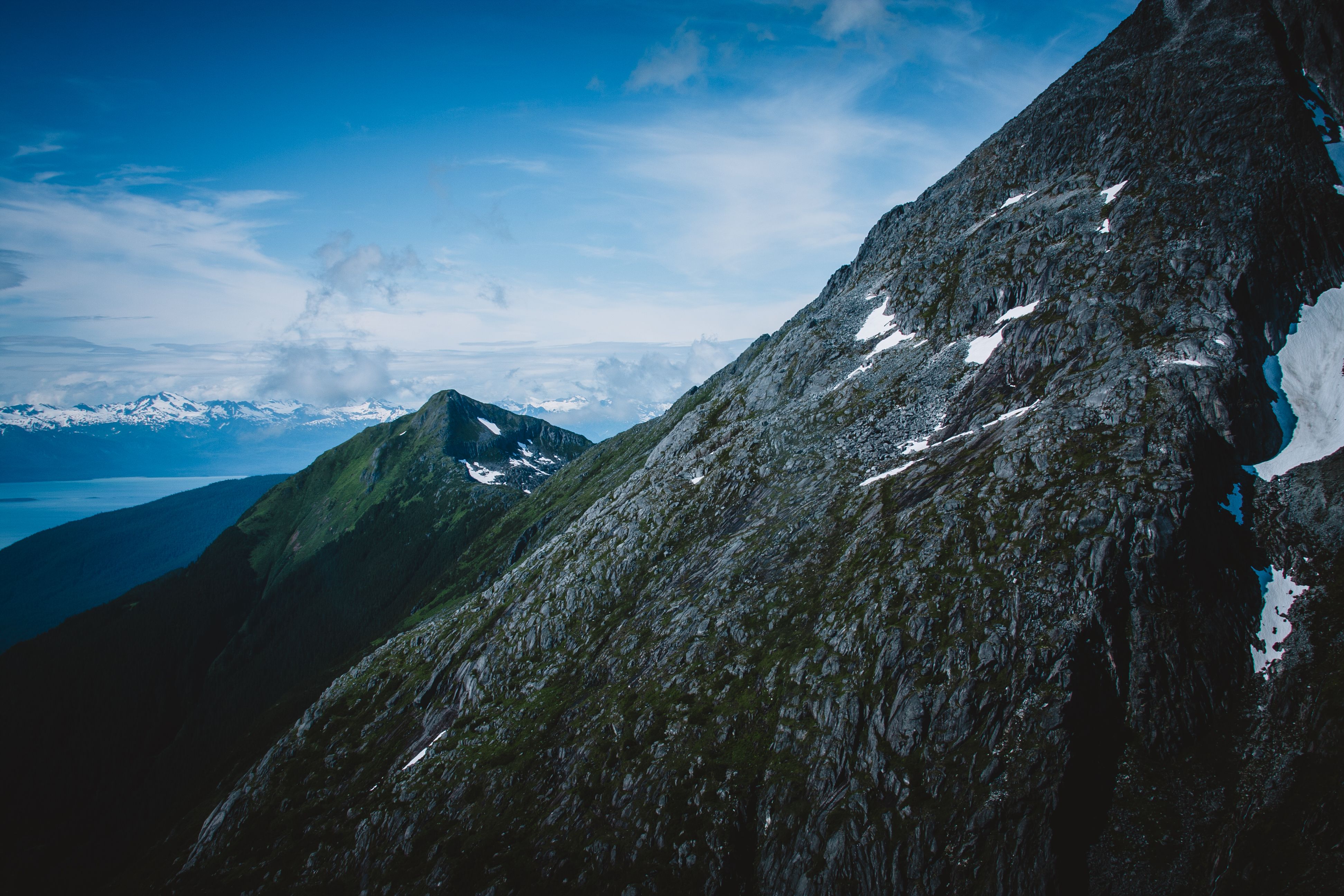 Helicopter to a Dogsledding Experience with a Glacier Landing - Stunning aerial view of rugged mountain landscape with snow-capped peaks under a clear blue sky.