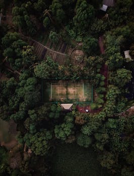 无人机拍摄的画面中，网球场坐落在泰国茂密的森林里，展现了自然美景