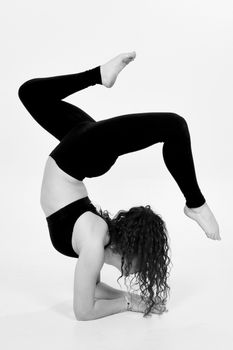 Black and white photo of a sportswoman in a dramatic handstand showcasing flexibility.