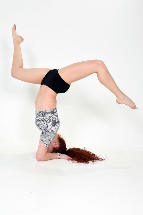 Free A woman in sportswear performing a headstand on a white background showcasing strength and balance. Stock Photo