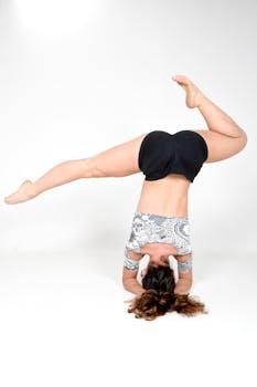 Female athlete performing a headstand yoga pose showcasing strength and flexibility in a studio setting.