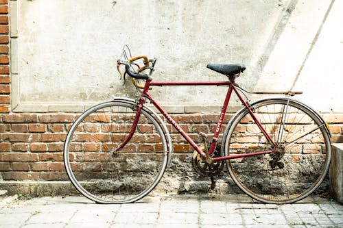 Bicicleta De Carretera Roja Inclinada Sobre Muro De Hormigón Blanco