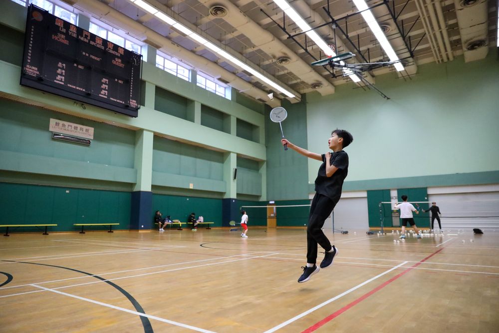 Badminton players training under indoor court lights