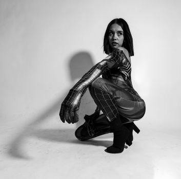 Studio shoot capturing model in spider costume, crouched pose in dramatic monochrome.