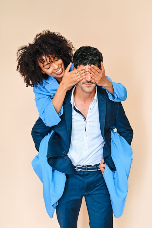 A man and woman in a blue suit covering their eyes