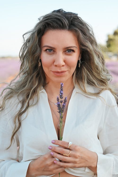 A woman holding a lavender flower in her hand
