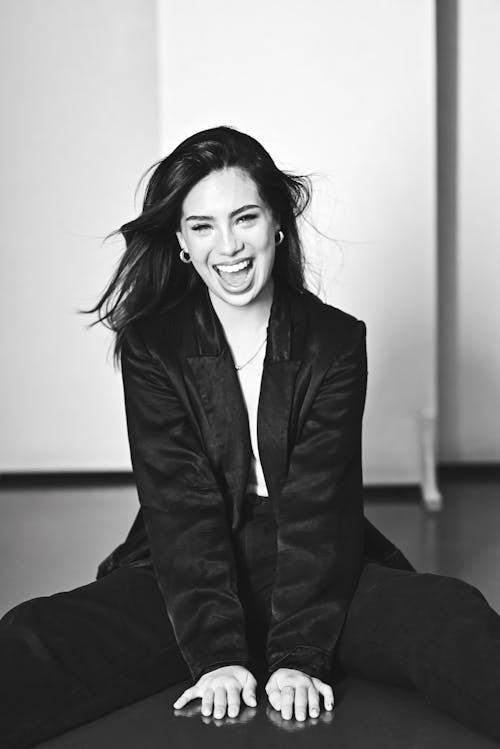 A woman in a black suit sitting on the floor