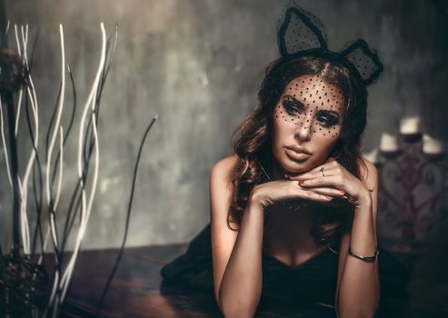 Stylish woman posing elegantly with a vintage vibe, wearing a polka dot veil and lace headpiece.