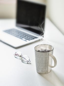 桌上放着咖啡、笔记本电脑和眼镜，非常适合生产力主题