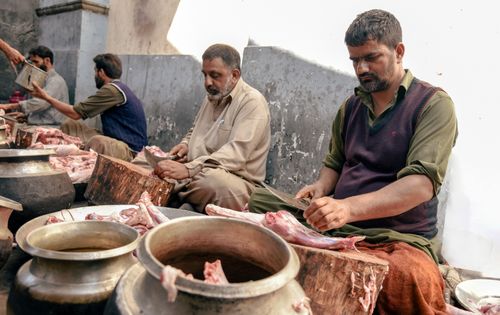 Free Men preparing mutton at a traditional market in Srinagar, showcasing local culture. Stock Photo