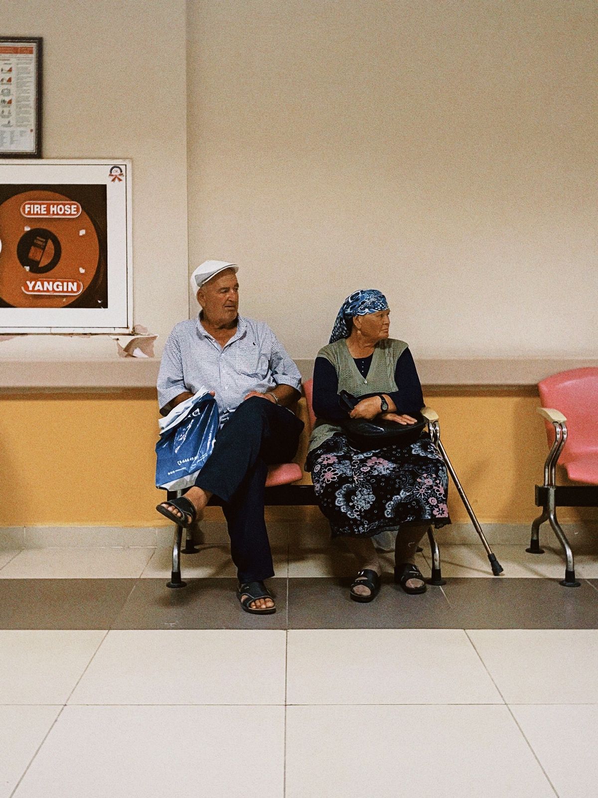A senior couple waiting in a hospital corridor seating area