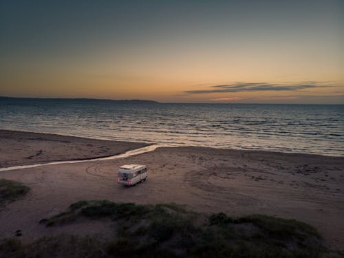 A van is parked on the beach at sunset