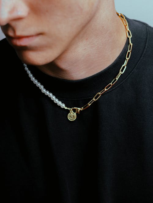 A man wearing a gold chain necklace with a pearl