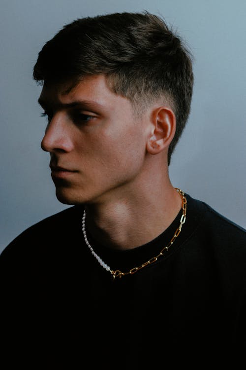 A young man with a black shirt and gold chain