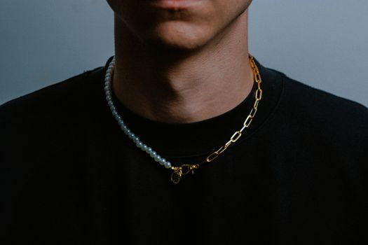 Close-up of a dual necklace on a man's neck, combining pearls and gold chain.
