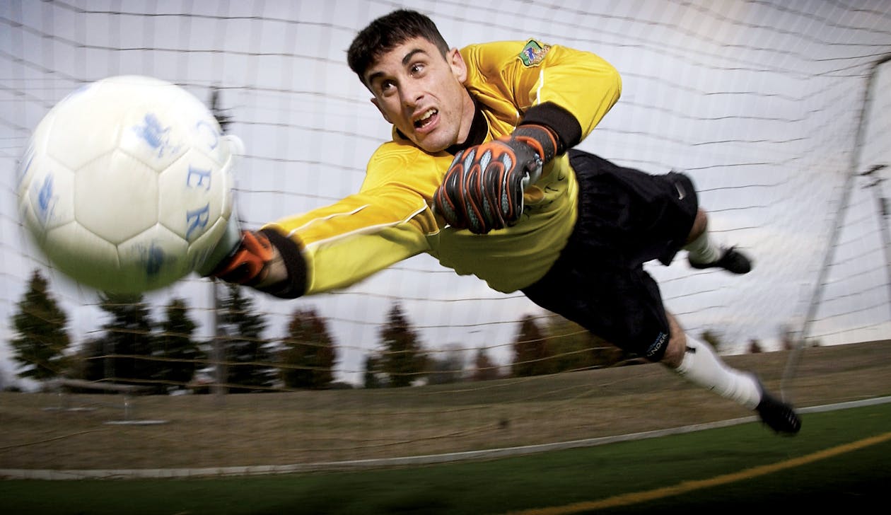 goleiro defendendo bola ao jogar futebol