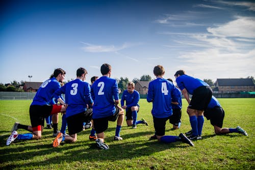 Free Group of Sports Player Kneeling on Field Stock Photo