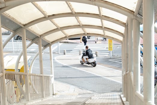 Person riding a scooter through a covered urban walkway, capturing the bustling city atmosphere.