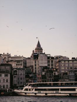 Scenic view of Galata Tower and cityscape with a ferry on the Bosphorus in Istanbul, Turkey.