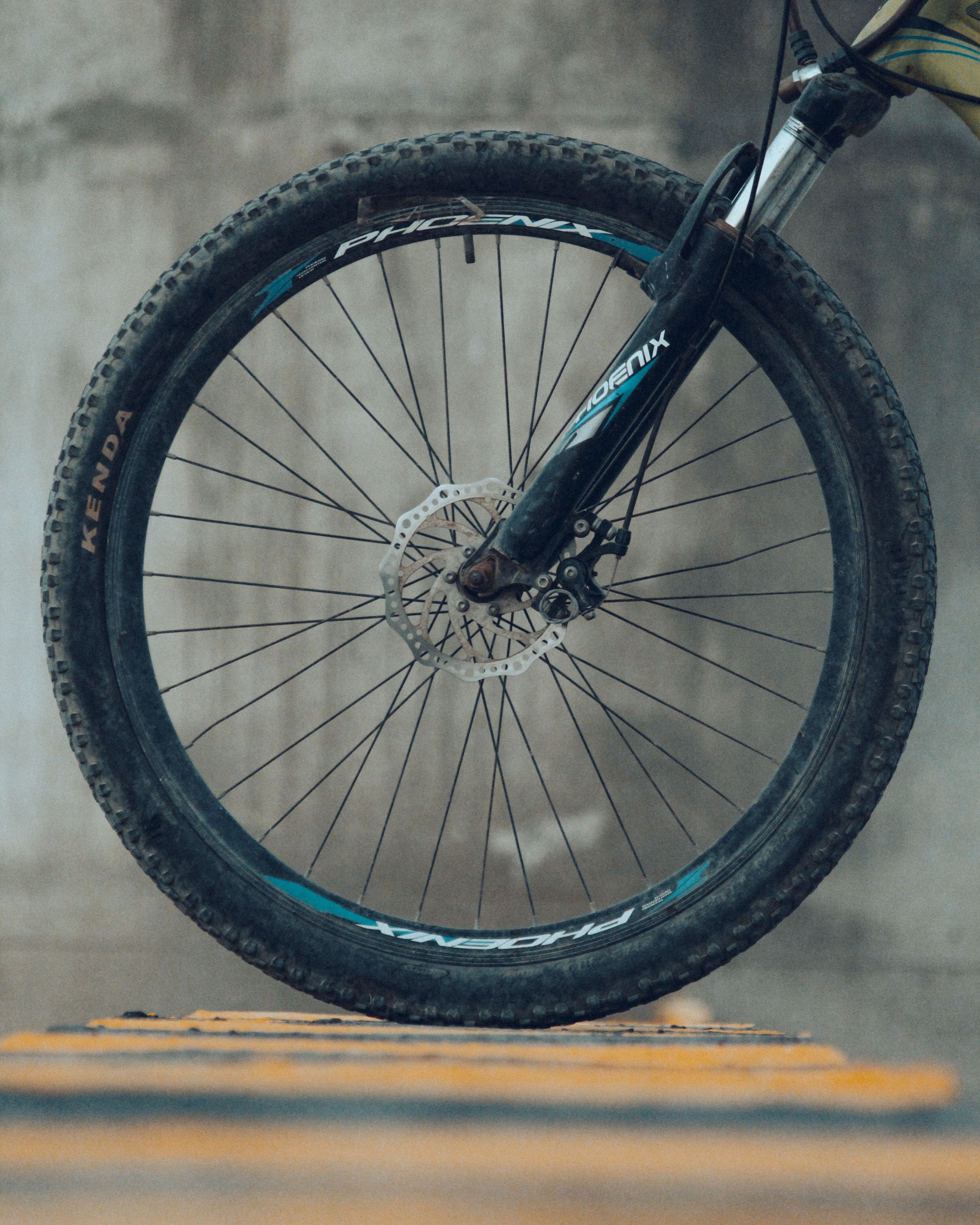 A detailed view of a mountain bike wheel resting on the street in an urban environment, India.